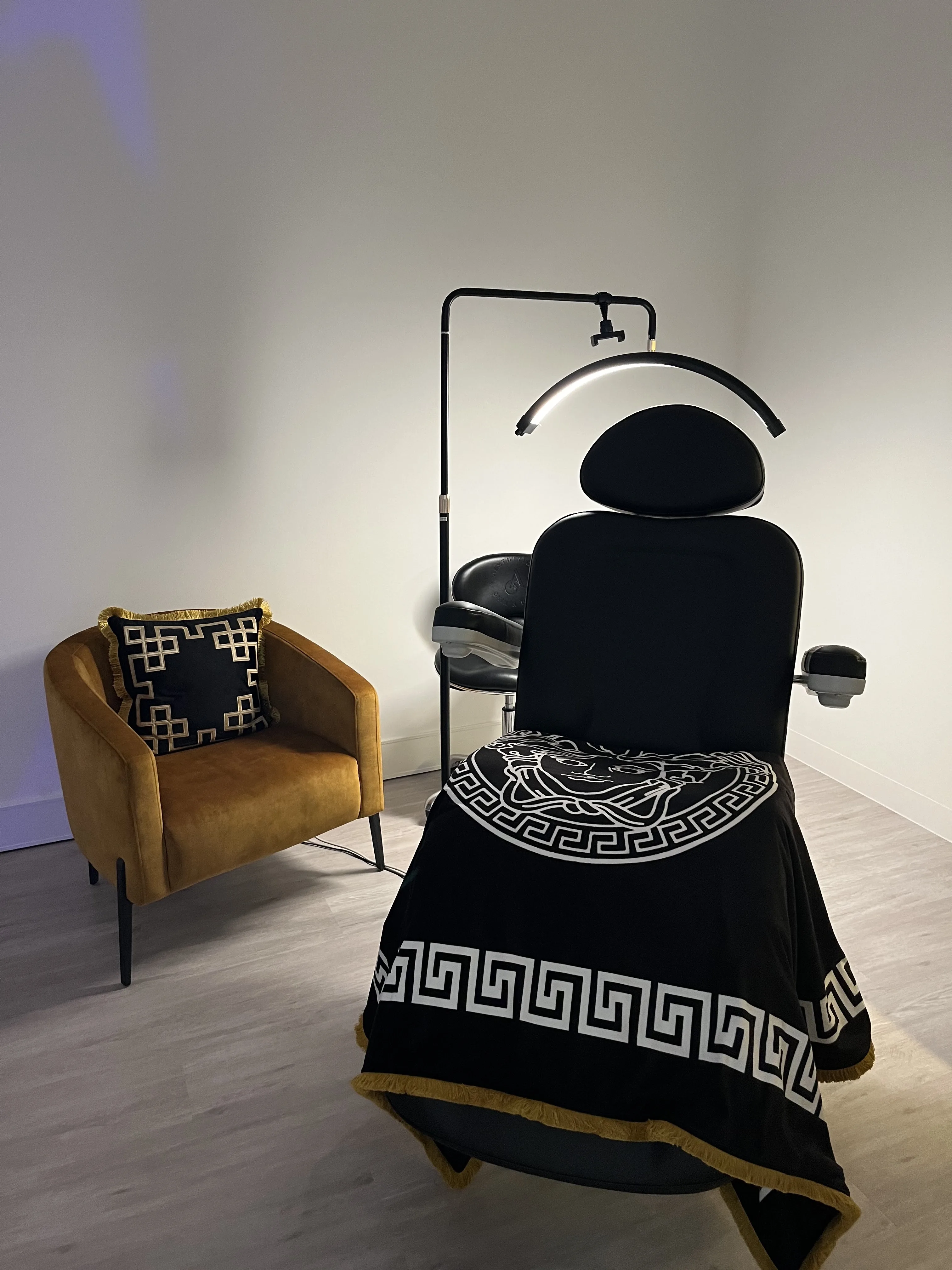 Treatment room — black treatment chair with gold fringe throw and mustard velvet armchair